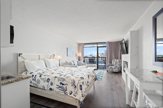 bedroom featuring dark hardwood / wood-style flooring, expansive windows, access to exterior, and a textured ceiling