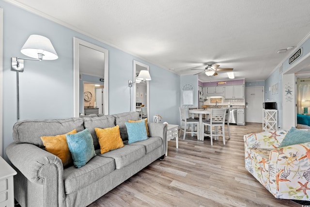 living room with crown molding, light hardwood / wood-style flooring, ceiling fan, and a textured ceiling