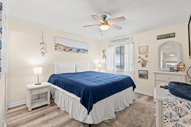 bedroom with a textured ceiling, light hardwood / wood-style flooring, ceiling fan, and crown molding