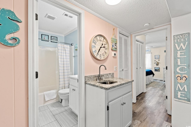 full bathroom with toilet, a textured ceiling, crown molding, and vanity