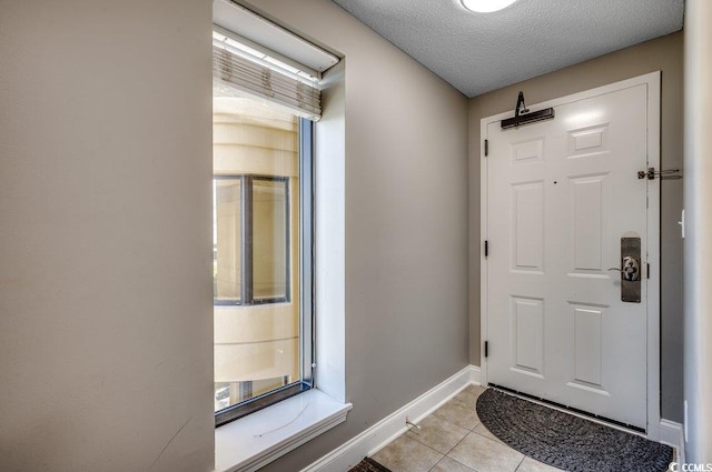 doorway with light tile patterned floors, baseboards, and a textured ceiling