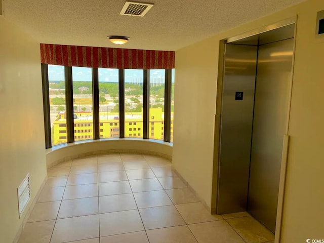 unfurnished room with elevator, visible vents, a textured ceiling, and light tile patterned flooring