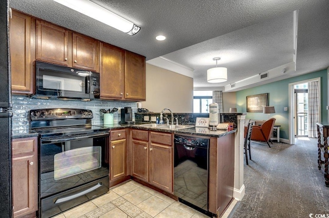 kitchen with tasteful backsplash, brown cabinetry, a peninsula, black appliances, and a sink