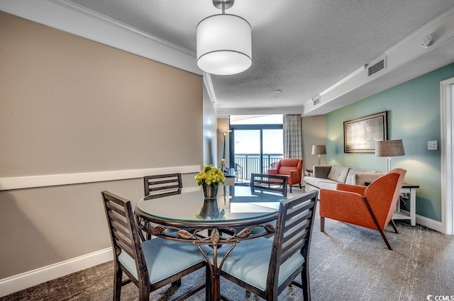 dining room featuring baseboards, visible vents, a textured ceiling, and ornamental molding