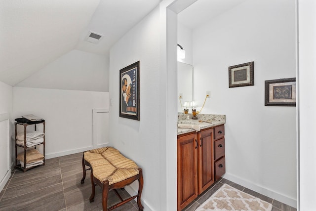 bathroom with tile patterned flooring, vaulted ceiling, and vanity