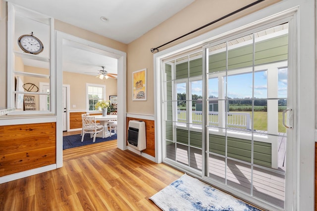 doorway to outside with light hardwood / wood-style floors, ceiling fan, and heating unit