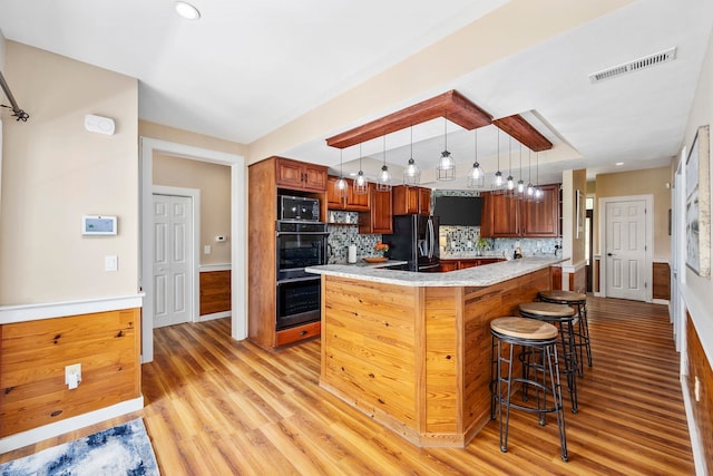 kitchen featuring pendant lighting, kitchen peninsula, light hardwood / wood-style floors, and tasteful backsplash