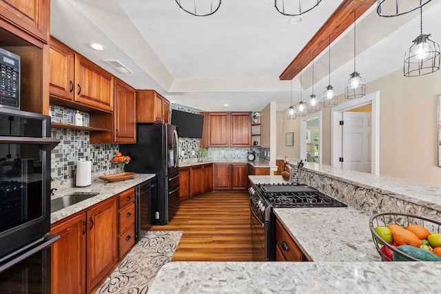 kitchen featuring light stone countertops, pendant lighting, light hardwood / wood-style flooring, gas range oven, and decorative backsplash