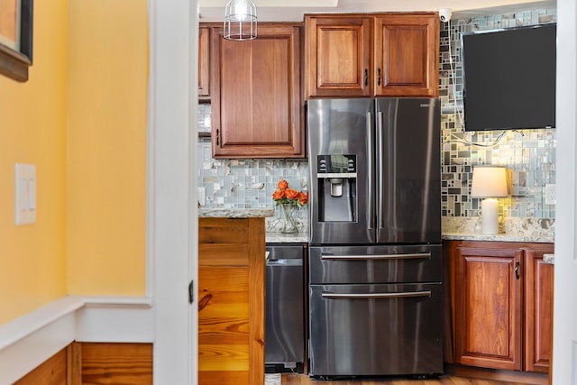 kitchen featuring stainless steel refrigerator with ice dispenser, backsplash, and light stone countertops