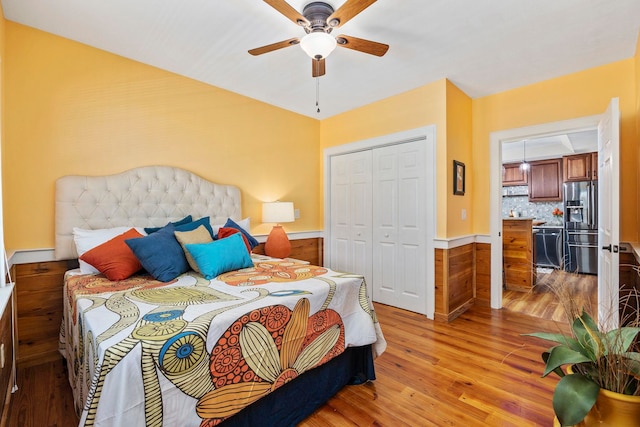 bedroom featuring light wood-type flooring, ceiling fan, stainless steel refrigerator with ice dispenser, and a closet