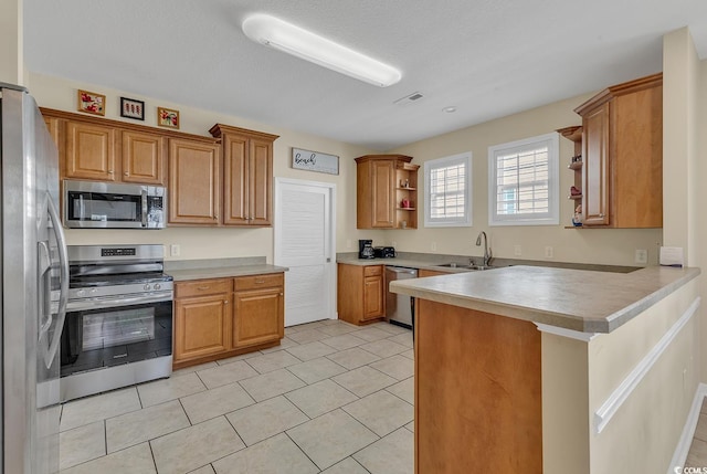 kitchen with a textured ceiling, stainless steel appliances, sink, kitchen peninsula, and light tile patterned flooring