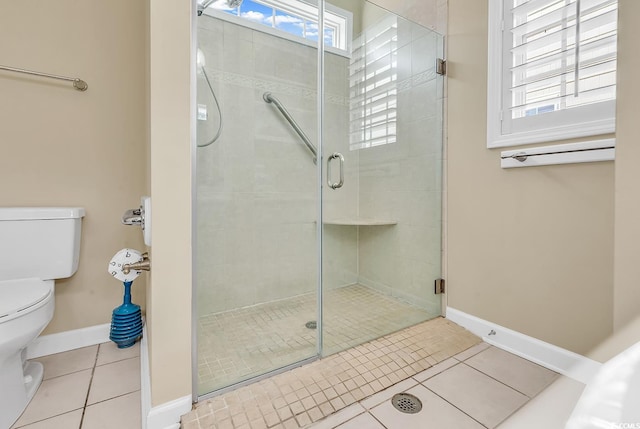 bathroom with toilet, plenty of natural light, a shower with shower door, and tile patterned floors