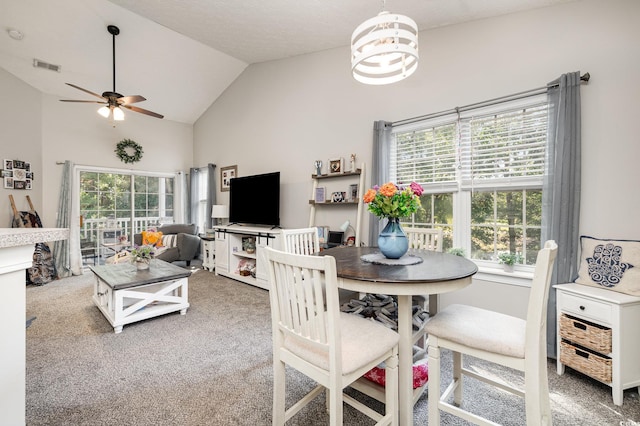 dining space with ceiling fan with notable chandelier, carpet flooring, vaulted ceiling, and a wealth of natural light