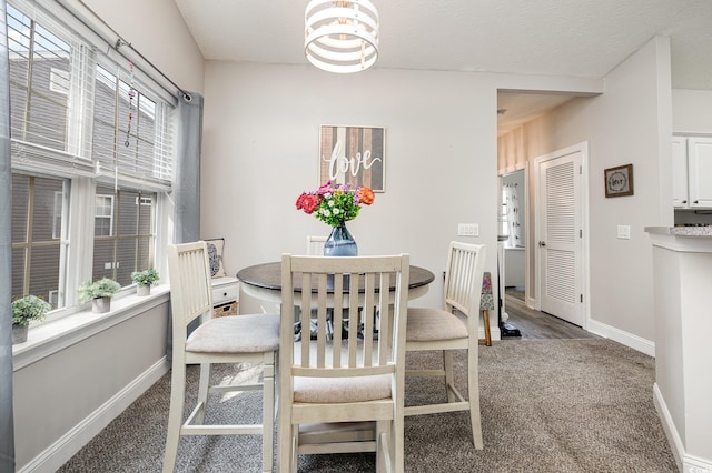 carpeted dining room with a textured ceiling, a chandelier, and plenty of natural light