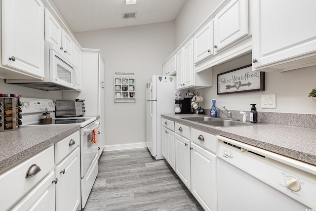 kitchen with vaulted ceiling, white cabinets, white appliances, light wood-type flooring, and sink