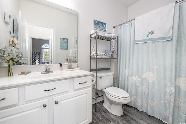 bathroom featuring hardwood / wood-style floors, walk in shower, vanity, and toilet