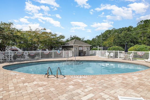 view of pool featuring a patio area and an outbuilding