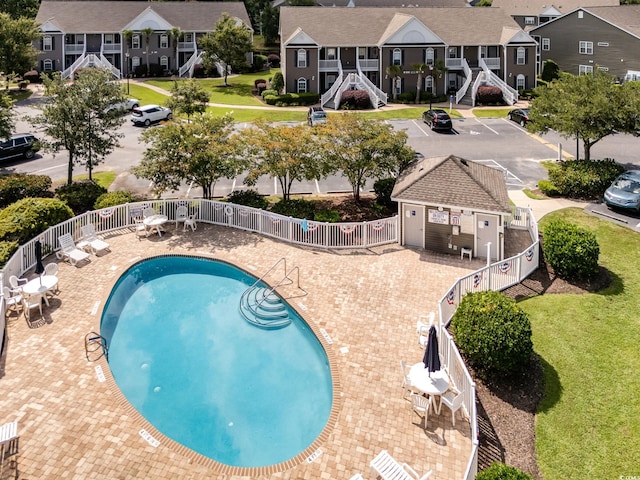 view of pool with a garage, a patio, a yard, and an outbuilding