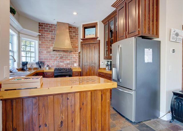 kitchen with black appliances, custom range hood, and sink