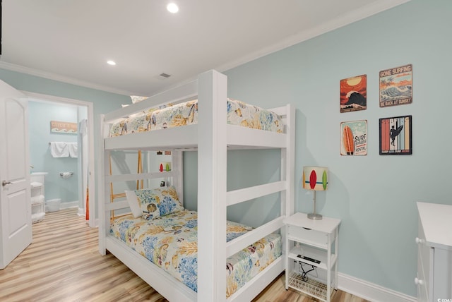 bedroom featuring light hardwood / wood-style floors, ornamental molding, and ensuite bath