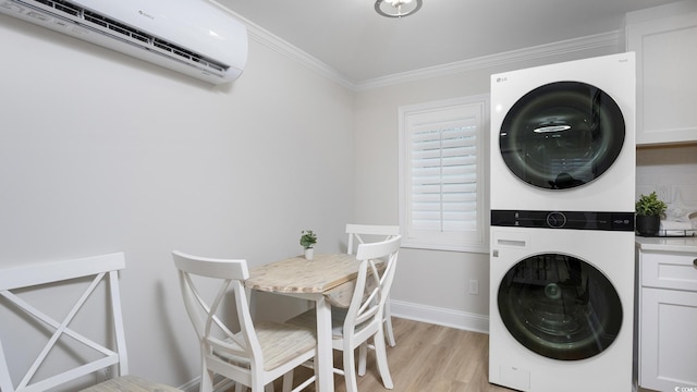 laundry area featuring ornamental molding, a wall mounted AC, light hardwood / wood-style flooring, cabinets, and stacked washer and dryer