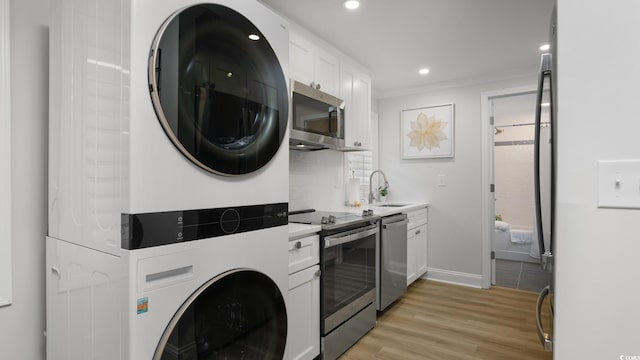 clothes washing area with sink, light hardwood / wood-style floors, crown molding, and stacked washer and clothes dryer