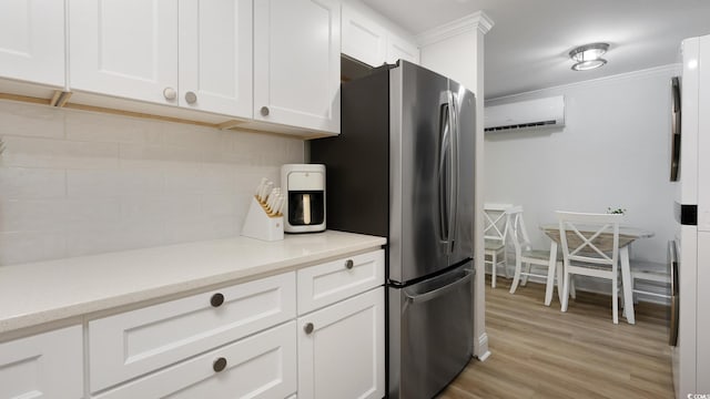 kitchen featuring a wall mounted AC, white cabinetry, stainless steel refrigerator, light wood-type flooring, and crown molding