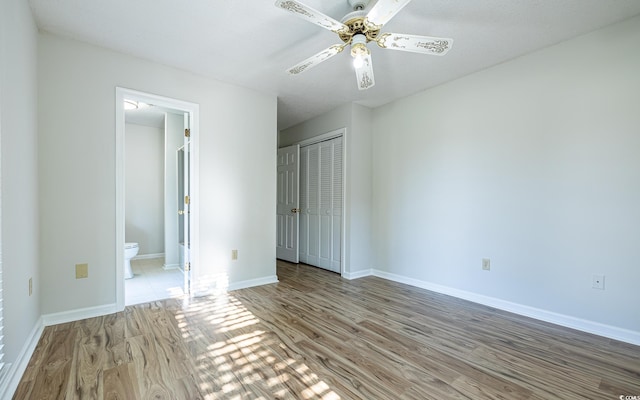 unfurnished bedroom with ceiling fan, light wood-type flooring, connected bathroom, and a closet