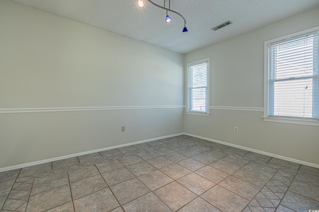 tiled empty room with a textured ceiling