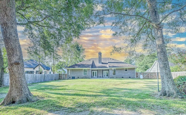 back house at dusk featuring a yard