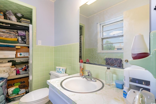 bathroom with toilet, vanity, and tile walls