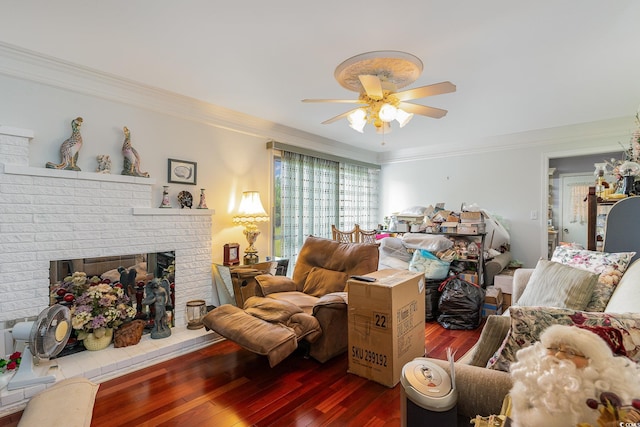 living room with a brick fireplace, ceiling fan, dark hardwood / wood-style flooring, and ornamental molding