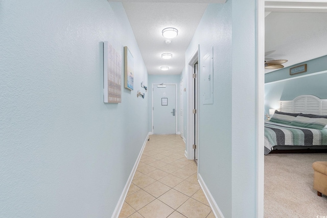 hall featuring light tile patterned floors and a textured ceiling