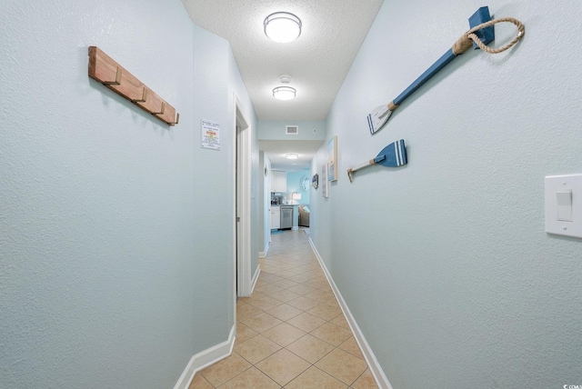 hallway featuring light tile patterned floors and a textured ceiling