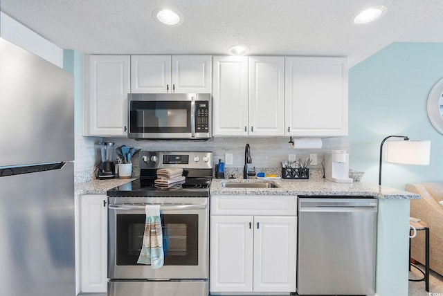 kitchen featuring white cabinetry, sink, backsplash, a textured ceiling, and appliances with stainless steel finishes