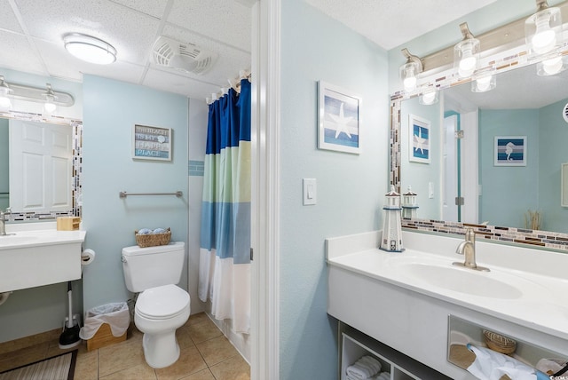 bathroom with a paneled ceiling, vanity, tile patterned flooring, a shower with shower curtain, and toilet