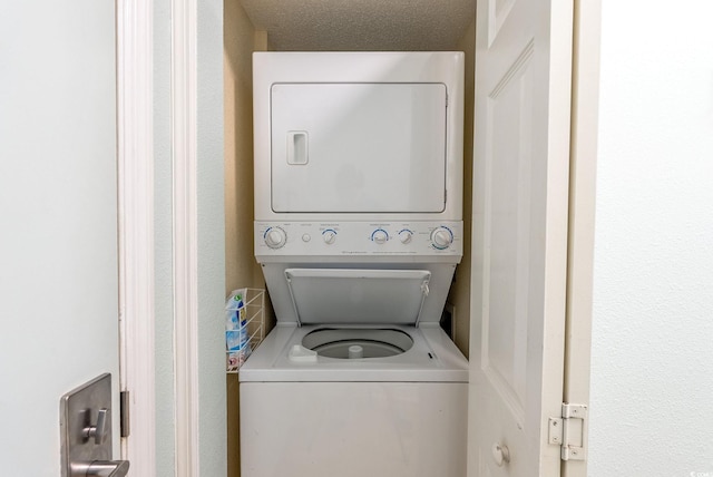 laundry area with a textured ceiling and stacked washer and clothes dryer