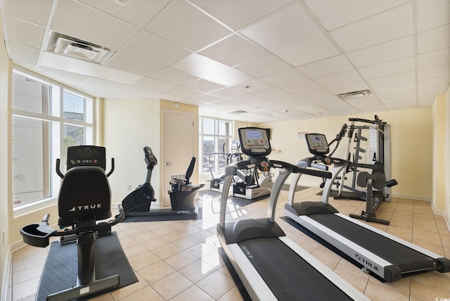 exercise room featuring a paneled ceiling and light tile patterned floors