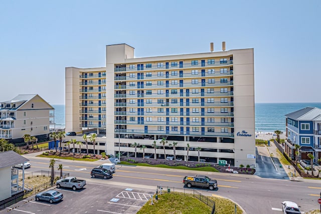 view of building exterior with uncovered parking and a water view