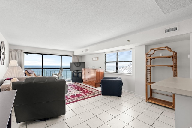 living room with a textured ceiling, light tile patterned floors, and visible vents