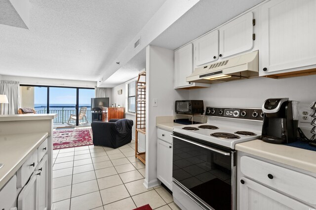 kitchen with white cabinets, a textured ceiling, light tile patterned floors, and white electric range oven