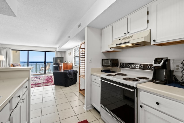 kitchen with white electric stove, light tile patterned floors, visible vents, open floor plan, and under cabinet range hood