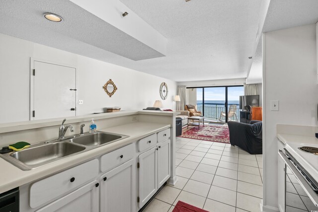 kitchen featuring light tile patterned floors, white stove, white cabinetry, sink, and a textured ceiling