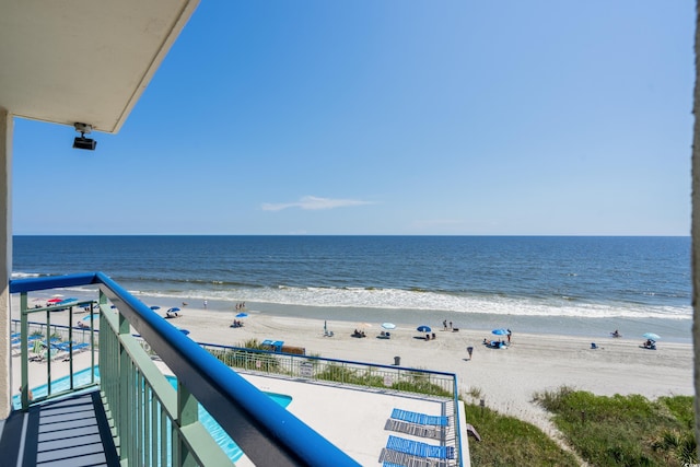 balcony with a water view and a view of the beach