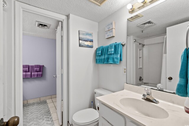 bathroom with tile patterned flooring, vanity, toilet, and a textured ceiling