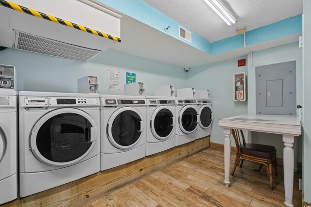 laundry area with electric panel, light hardwood / wood-style flooring, and washer and clothes dryer