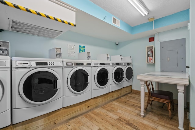 community laundry room featuring visible vents, light wood finished floors, electric panel, and washer and dryer