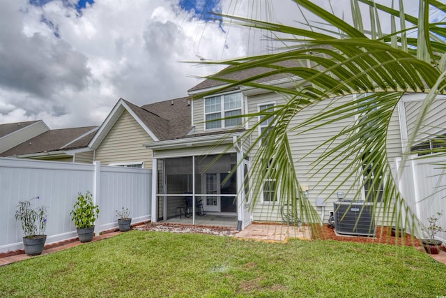 rear view of property with a lawn, central AC, a patio, and a sunroom