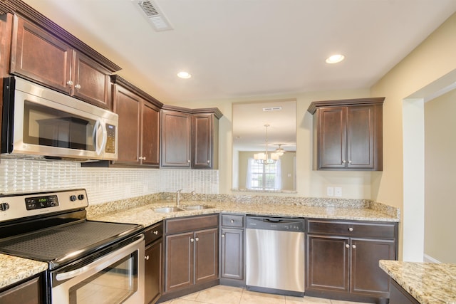 kitchen with light stone countertops, a notable chandelier, light tile patterned floors, stainless steel appliances, and sink