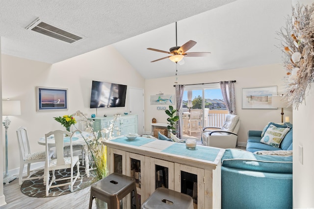 living room with lofted ceiling, ceiling fan, a textured ceiling, and light hardwood / wood-style flooring